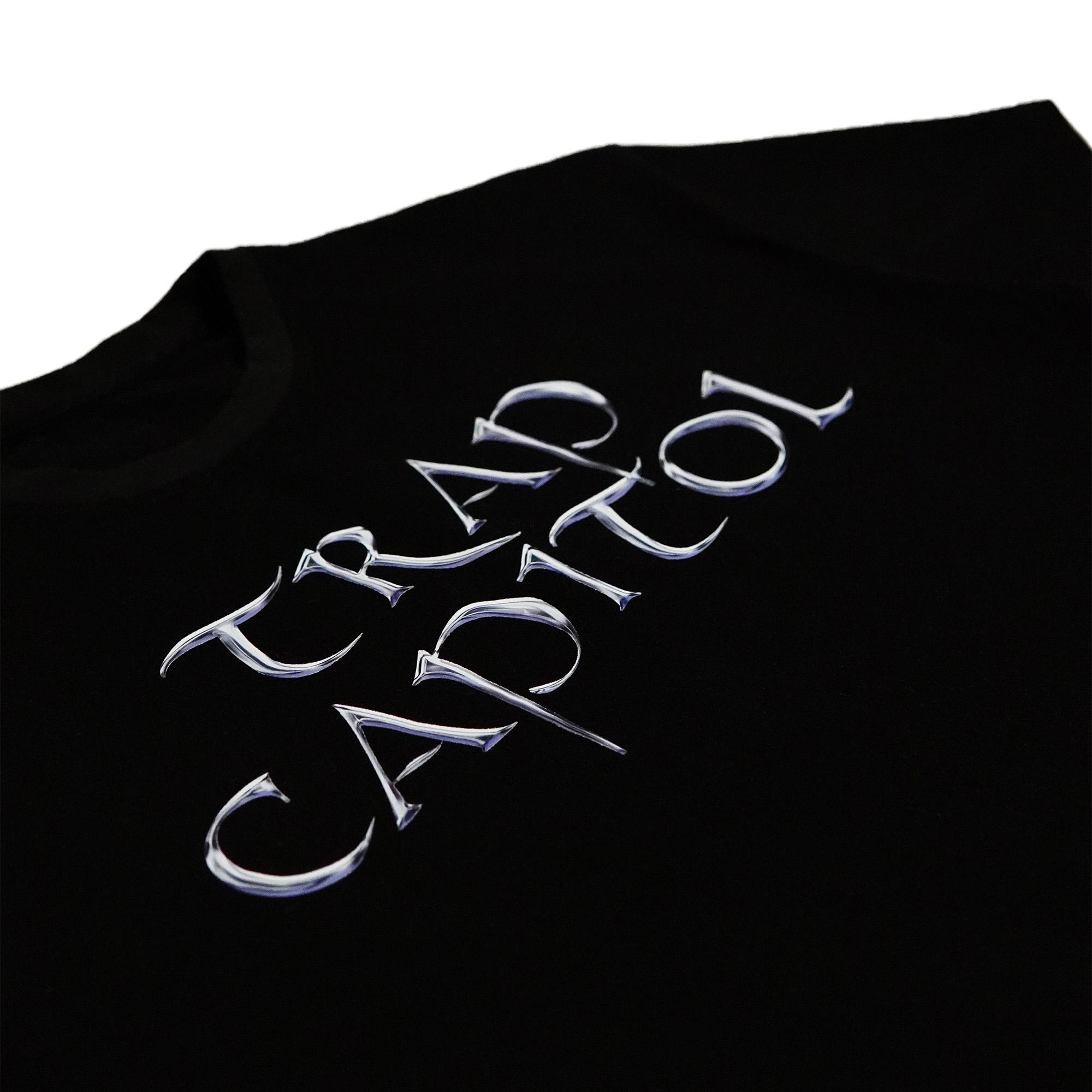 Close-up angled shot of a black t-shirt focusing on the detailed metallic 'TRAP CAPITOL' typography print